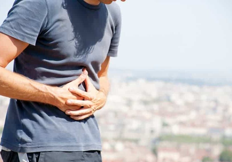 a man holding his stomach in pain from digestive problems