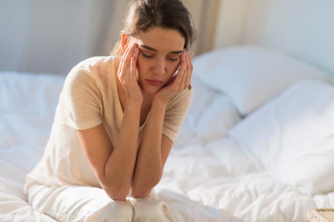 a female showing hormonal imbalance symptoms by holding her temples